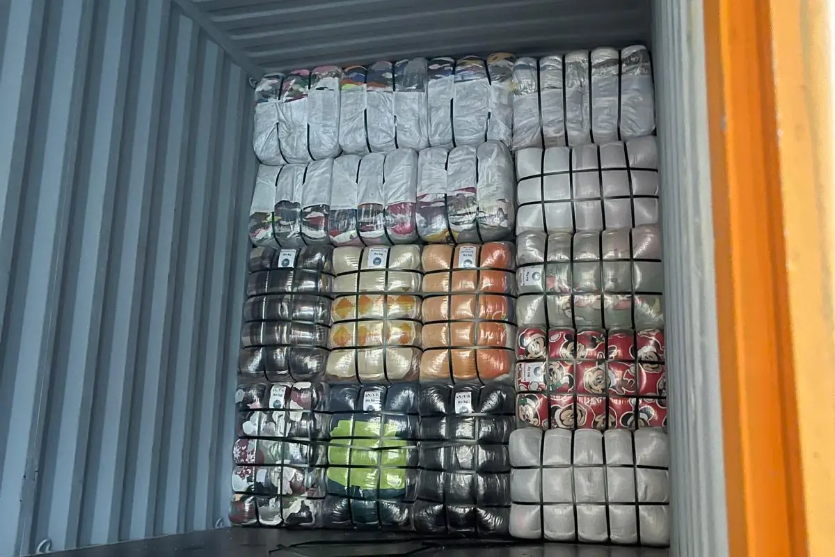 Container being loaded with different types of labelled clothing bales