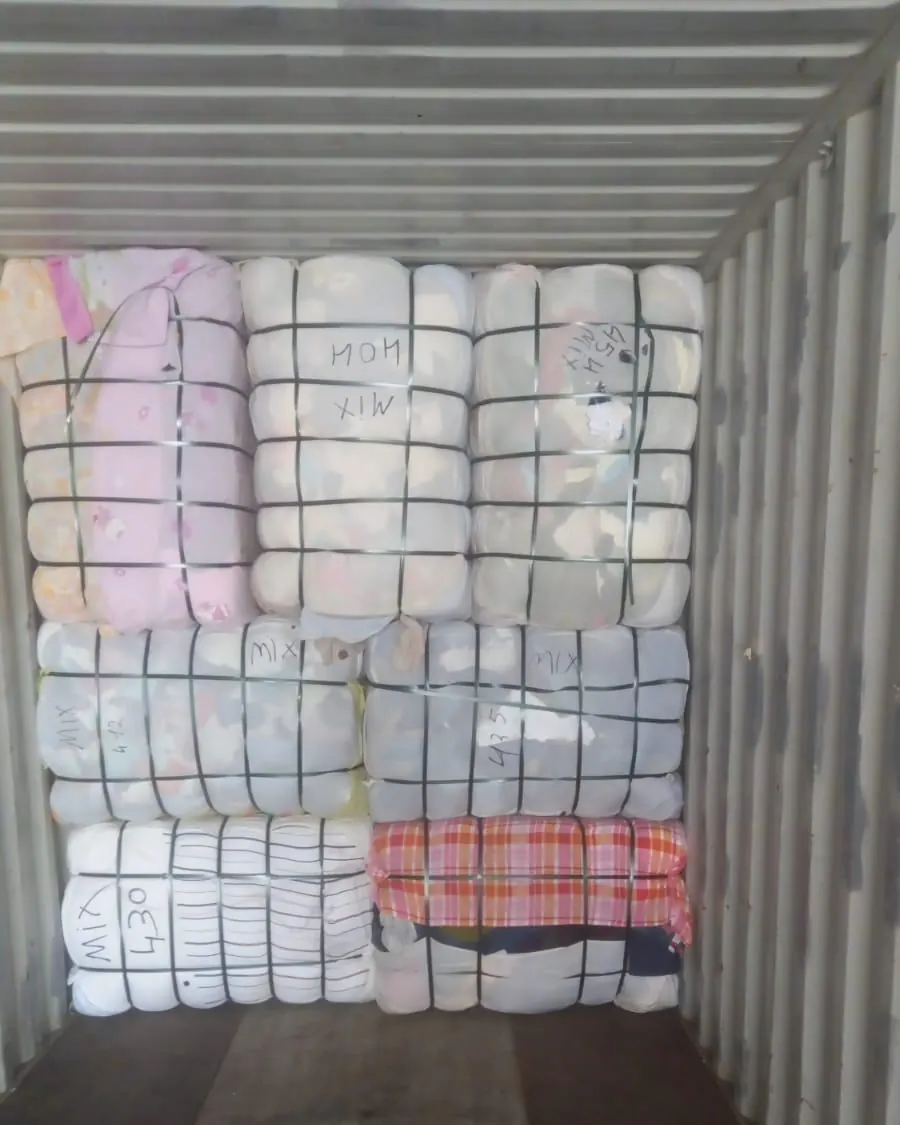 Mixed clothing bales marked by hand inside a container